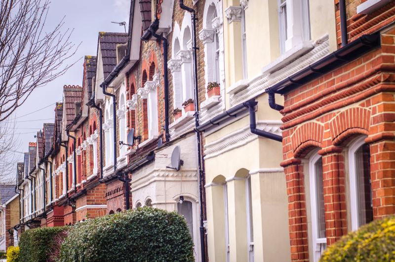 A row of traditional English terraced houses, pictured on a cloudy day.