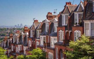 A row of traditional terraced houses on a hill that overlooks a city, pictured on a sunny day.