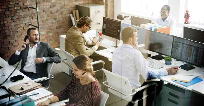 A wide angle view of employees working at their desks in a modern office.