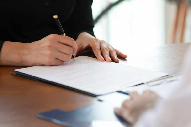 A closeup image of a female client signing a document during a consultation with a solicitor.