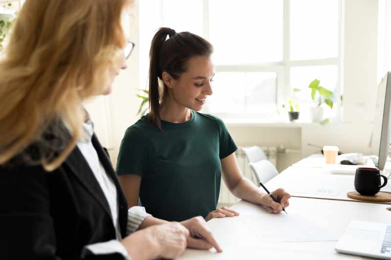 A young woman sits with a solicitor and signs a form to appoint an attorney.