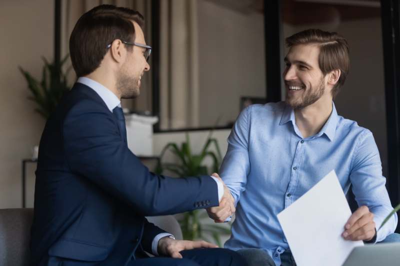 A professional solicitor and a happy male client shake hands