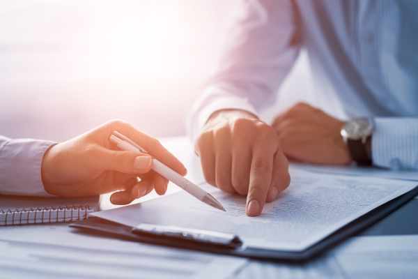 A male solicitor reviews a settlement agreement with his male client.