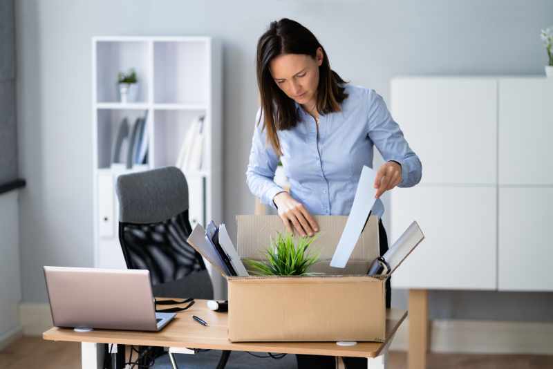 A dismissed employee packs her personal possessions into a cardboard box.